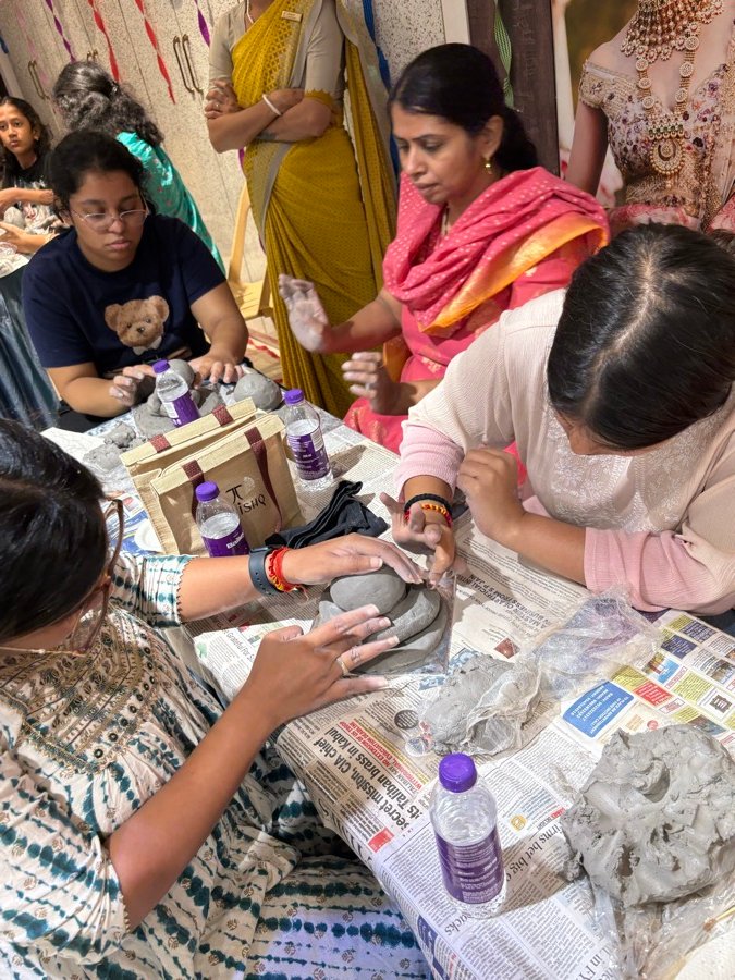 Hands shaping wet clay at a table full of workshop participants